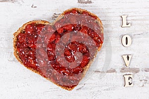 Bread in shape of heart with strawberry jam and inscription love. Rustic background