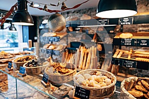 Bread shop showcase. Braided baskets with various buns, shelves with bread and a shop window with sandwiches.