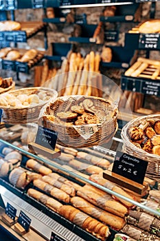 Bread shop showcase. Braided baskets with various buns, shelves with bread and a shop window with sandwiches.