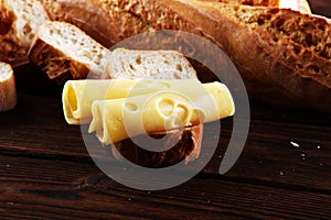 Bread with slices of cheese for lunch table. Sharing antipasti on party or summer picnic time over wooden rustic background