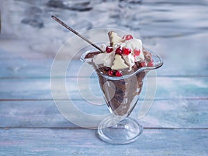 Bread soup with whipped cream, red currants and chocolate in a tall glass bowl