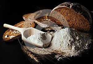 Bread, spikelets of wheat on a black background. Flour is the main ingredient for baking