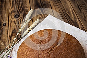 Bread and spikelets of wheat on a wooden background