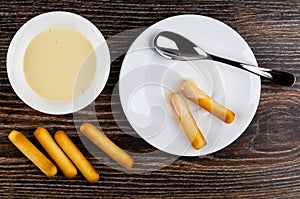 Bread sticks, condensed milk, teaspoon, breadsticks with milk on