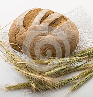 Bread on a table with wheat lies on a lace napkin