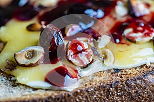 Bread toast with butter, roasted hazelnuts, honey, berry jam on plate , closeup