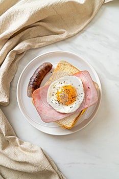 Bread toasted cheese topped ham and fried egg with pork sausage