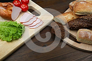 bread, tomato, chopped ham and lettuce on cutting boards