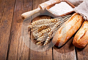 Bread with wheat ears and bowl of flour