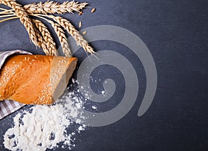 Bread, wheat ears and flour on the black background