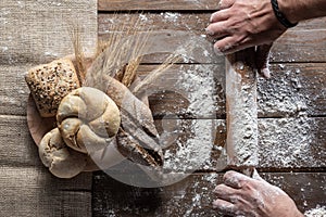 Bread with wheat ears and flour on wood board, top view