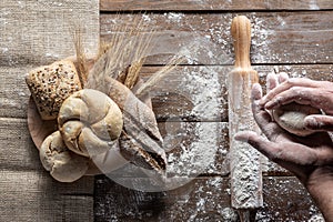 Bread with wheat ears and flour on wood board, top view