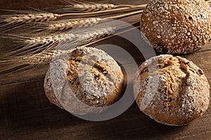 Bread and wheat ears on wooden background