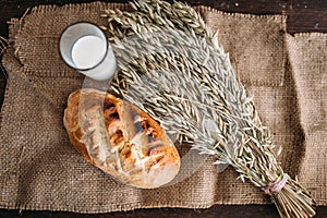 Bread, wheat and glass of milk, burlap background