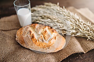 Bread, wheat and glass of milk, burlap background