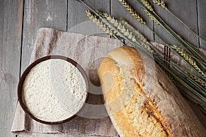 Bread wheat spike and flour on wooden background