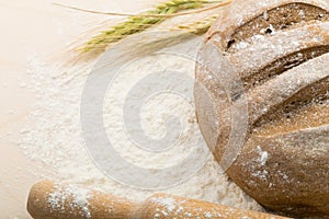 Bread on a wooden boar with flour and wheat ears