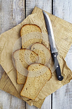 Bread on wooden board. Homebaked bread. Natural food. Slices of bread and a knife on a wooden table