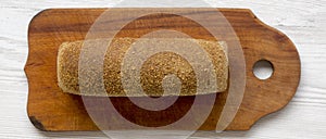 Bread on wooden cutting board on white woodem surface, overhead. From above. Top view