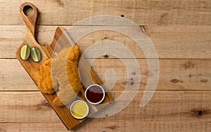 Breaded chicken filet, served with mustard and ketchup, on a wooden background. top wiew
