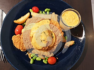 Breaded chicken with fried potatoes wedges and cheese sauce