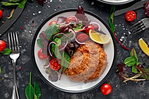 Breaded Chicken Kiev breast stuffed with butter, garlic and herbs served with vegetables in a plate.