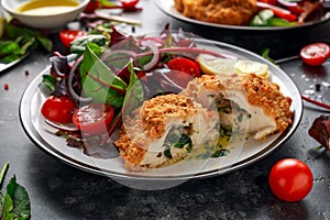 Breaded Chicken Kiev breast stuffed with butter, garlic and herbs served with vegetables in a plate. photo