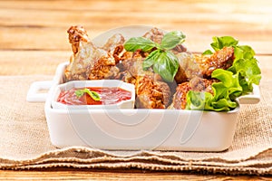 Breaded chicken wings.Fried breaded chicken wings with lettuce and with ketchup on a wooden background. fast food, close-up