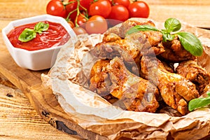 Breaded chicken wings.Fried breaded chicken wings with lettuce and tomatoes on wooden background close up