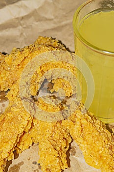 Breaded chicken wings and a glass of lemonade on a grey paper background. Close up