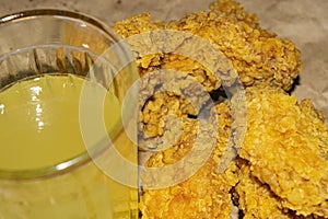 Breaded chicken wings and a glass of lemonade on a grey paper background. Close up