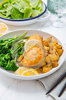 Breaded fisch fillet with spicy baked potatoes and broccoli bimi salad