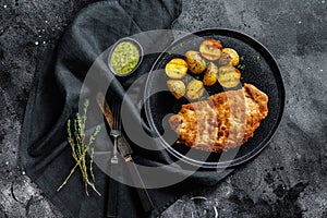 Breaded german weiner schnitzel with potatoes. Black background. Top view