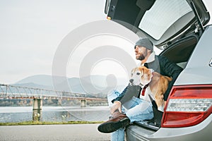 Breaded man in warm casual autumn outfit siting with beagle in c