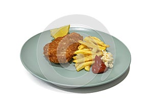 Breaded steak with French fries, with ketchup and mayonnaise, two lemon wedges, served on a turquoise plate.