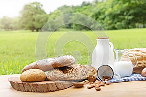 Breads and milk on wood table with blurred green garden background