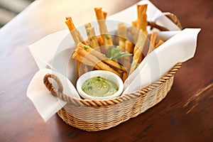 breadsticks in a napkin-lined basket with dips on the side