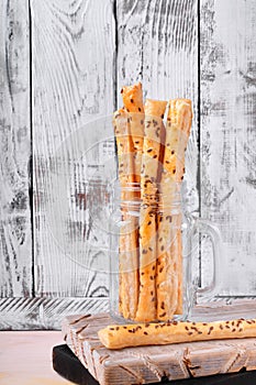Breadsticks of puff pastry with flax seeds in a glass jar