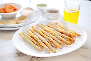 breadsticks with sesame seeds on a white platter