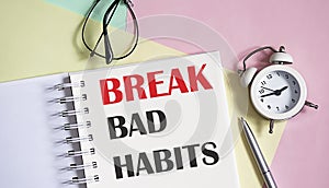 BREAK BAD HABITS on the notebook with pen,alarm clock on pink background