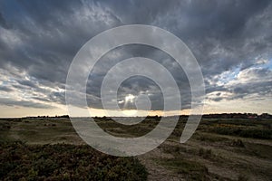 A break in the clouds. Bleak landscape with distant sun breaking