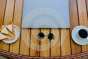 Break concept. Flat lay view of a workspace with a closed laptop on a brown wooden table, with a cup of coffee