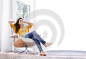 Break, relax and woman in a chair in a home with tired, smile and calm in a lounge and living room. Happy, chill and