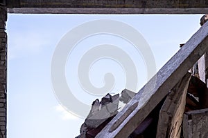 A break in the wall of a building with a pile of large concrete fragments against a background of clear sky. Background