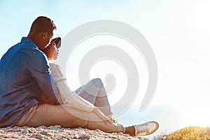 Breakaway with the one you love. a happy young couple sitting on a rock and enjoying the ocean view.