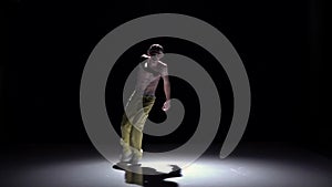 Breakdance dancer in yellow suit goes on dance on black, shadow, slow motion