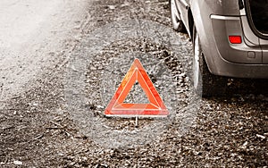 Breakdown of car. Red warning triangle sign on road