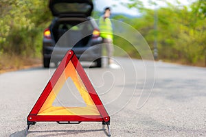 Breakdown triangle sign on road with worried Asian man talking by mobile phone with insurance or car service center company after