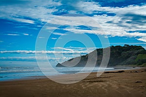 Breakers rolling over vast sand beach. Thick mist over ocean beach on a stormy day. Makorori beach, Gisborne, North