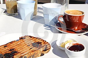 Simple breakfast with coffee, toast, butter and jam served outside